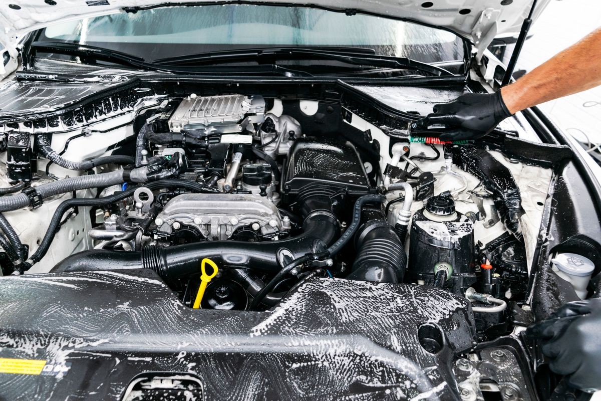 Cars in a carwash. Car wash with foam at station. Carwash. Washing at the station. Car washing concept. Car detailing. A man cleaning car. Worker cleaning. Cleaning engine with the foam and a brush