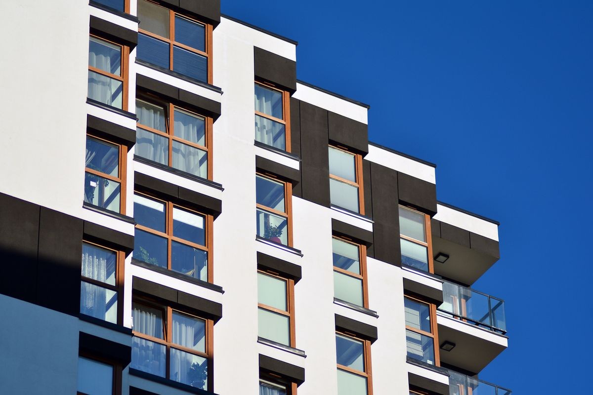 Fragment of a facade of a building with windows and balconies. Modern home with many flats.