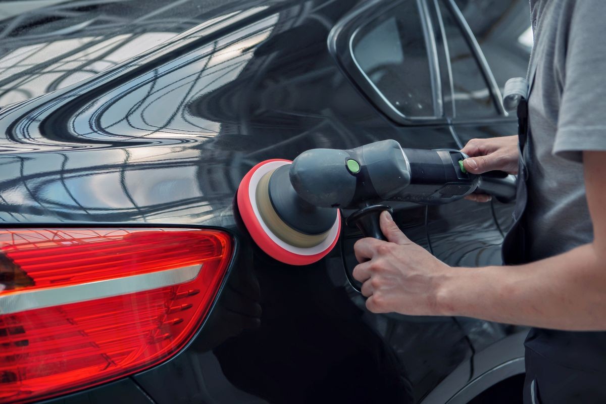 polishing machine on the surface of the black car close-up